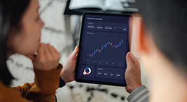 Eine Frau und eine Mann halten gemeinsam ein Tablet auf dem eine Auswertung angezeigt wird 